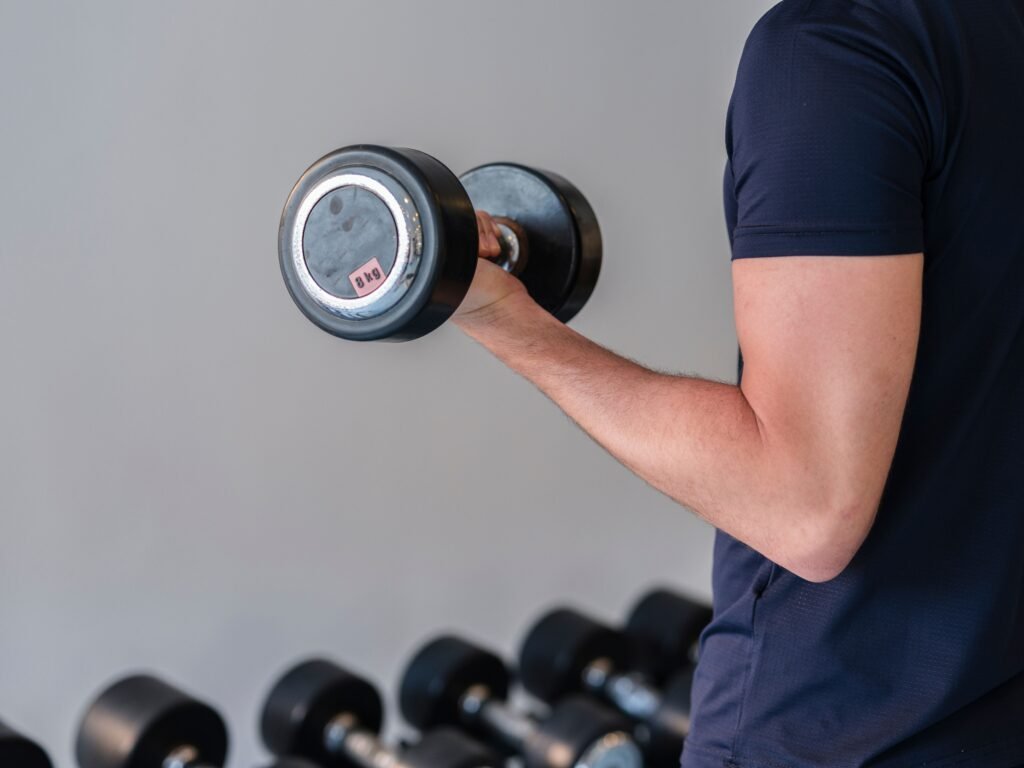Best Adjustable Dumbbells for Men Over 40: 7 Options Compared Close-up of a man lifting a dumbbell in a gym, emphasizing fitness and strength training.
