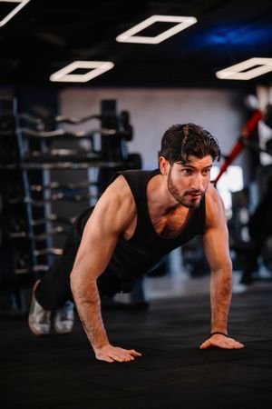 A muscular man performing push-ups in a modern gym, demonstrating strength and fitness.
